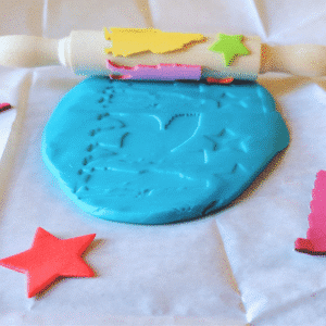 Cylinder seal craft with a decorated wooden roller making impressions in blue modelling dough